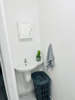 a white bathroom with a sink and a trash can at Self catering one bedroom cottage in Cape Town