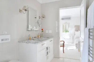 a white bathroom with a sink and a mirror at Farm Lorraine The Loft Cottage in Franschhoek