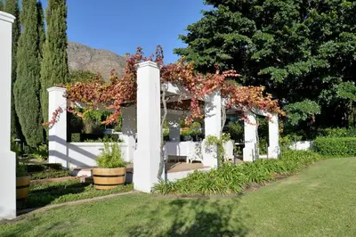 a white pergola with flowers on it in a yard at Farm Lorraine The Loft Cottage in Franschhoek