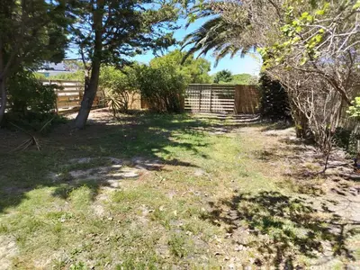 a yard with a fence and trees and grass at Rustig by die See in Bettyʼs Bay
