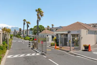 a street with houses with a gate and palm trees at 323 Leisure Bay in Cape Town