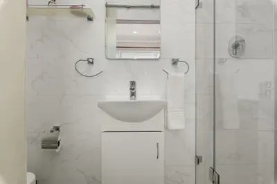 a white bathroom with a sink and a shower at 323 Leisure Bay in Cape Town