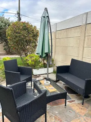 a patio with a table and a green umbrella at La Casetta, Garden Retreat in Cape Town