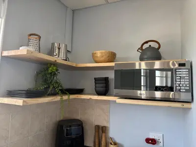 a microwave sitting on a shelf in a kitchen at Windpomp Self Catering in Paarl