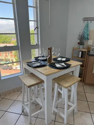 a white table with two chairs and a table with wine glasses at Windpomp Self Catering in Paarl