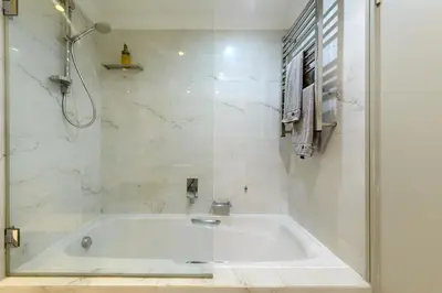 a white bathroom with a tub and a shower at Dolphin beach Apartment -Kite beach in Cape Town