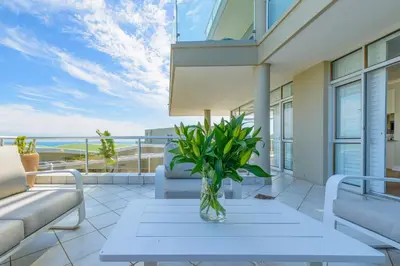 a patio with a table with a vase on it at Dolphin beach Apartment -Kite beach in Cape Town