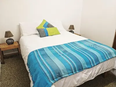 a bed with a blue and white blanket and two lamps at Mogit-ewig-duur in Hermanus