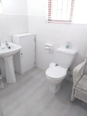 a white bathroom with a toilet and a sink at Mogit-ewig-duur in Hermanus