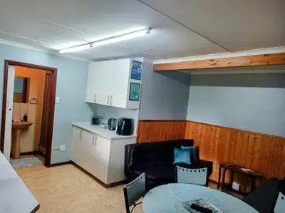 a living room with a table and a kitchen at LAAT Slaap Self-Catering Accommodation in Kleinmond