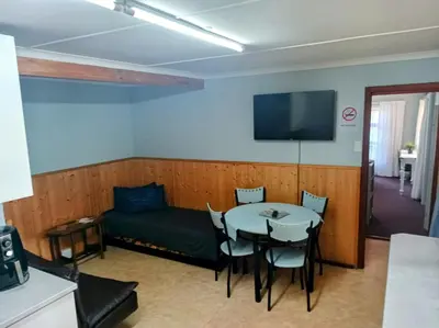 a room with a table and a couch and a tv at LAAT Slaap Self-Catering Accommodation in Kleinmond