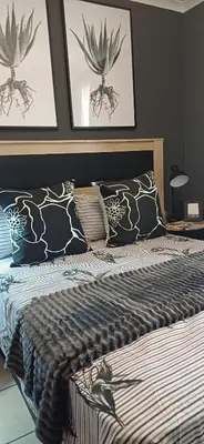 a bedroom with a bed with black and white pillows at V's Condo in Gordonʼs Bay