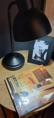 a black lamp sitting on top of a table with a magazine at V's Condo in Gordonʼs Bay