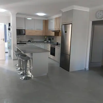 a kitchen with white cabinets and a stainless steel refrigerator at 107 St Tropez Eyrie Holiday Apartments in Cape Town