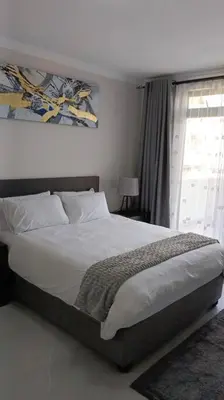 a bedroom with a large bed and a window at 107 St Tropez Eyrie Holiday Apartments in Cape Town
