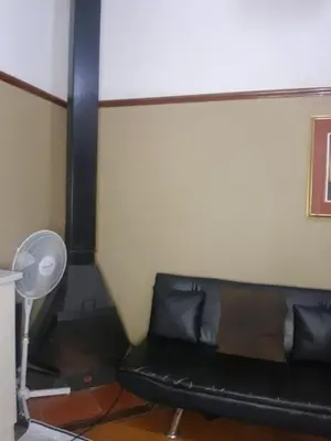 a black couch in a room with a fan at Room Parow, Cape Town in Cape Town