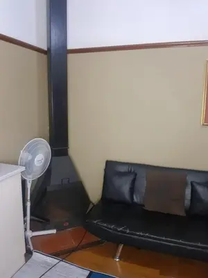 a black couch in a room with a fan at Room Parow, Cape Town in Cape Town