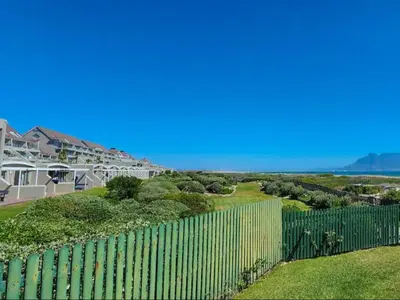 a fence in front of a house with the ocean in the background at Dolphin Delight in Bloubergstrand