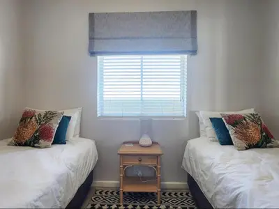 two twin beds in a room with a window at Dolphin Delight in Bloubergstrand