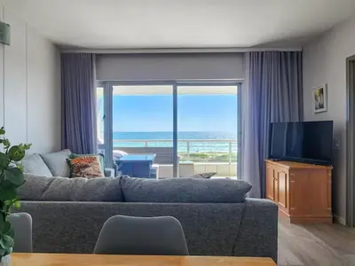 a living room with a couch and a television at Dolphin Delight in Bloubergstrand