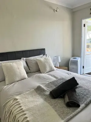 a large white bed with a blanket on top of it at Charming Flatlet Near the Amazing Sunset Beach in Cape Town