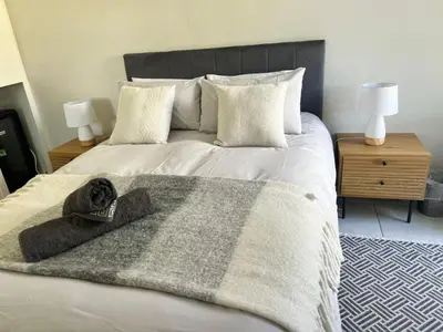a bed with a blanket and a hat on it at Charming Flatlet Near the Amazing Sunset Beach in Cape Town