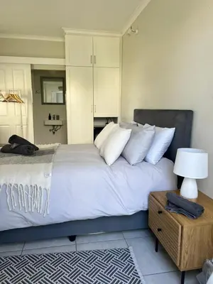 a bedroom with a large bed with white pillows at Charming Flatlet Near the Amazing Sunset Beach in Cape Town