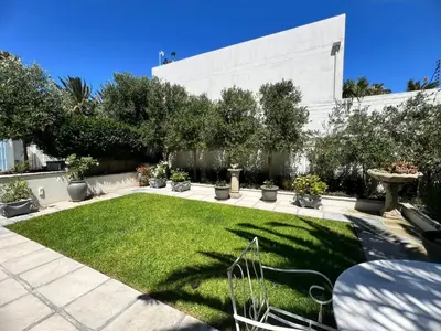 a garden with a lawn and a building at Charming Flatlet Near the Amazing Sunset Beach in Cape Town