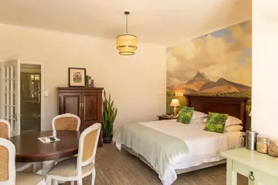a bedroom with a bed and a table and a painting at Mitre's Edge Simonsberg Studio in Klapmuts
