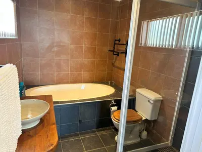 a bathroom with a tub and a toilet and a sink at Lily's Lodge in Somerset West