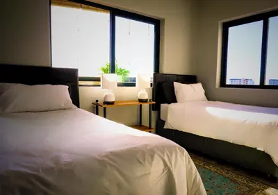 a bedroom with two beds and two windows at Knightsbridge Luxury Escape in Cape Town