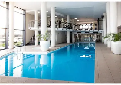a large swimming pool in a building with blue water at Knightsbridge Luxury Escape in Cape Town