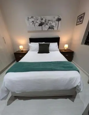 a bedroom with a large white bed with a green blanket at A cozy retreat - feels like home in Cape Town