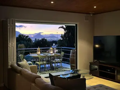 a living room with a couch and a large glass window at Bonita Vista Plattekloof in Cape Town