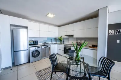 a kitchen with a table and chairs and a refrigerator at Top Floor Beachfront w Views, Blouberg, 51 Beach Break in Bloubergstrand