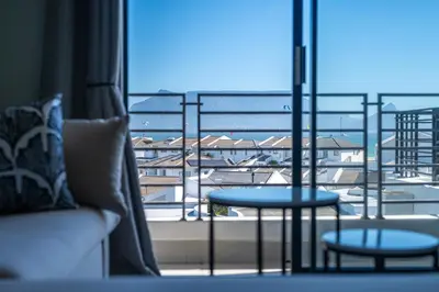 a balcony with a table and a view of a city at Top Floor Beachfront w Views, Blouberg, 51 Beach Break in Bloubergstrand