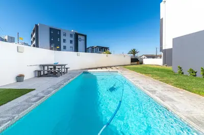 a swimming pool with a table on a building at Top Floor Beachfront w Views, Blouberg, 51 Beach Break in Bloubergstrand