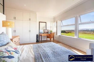 a bedroom with a bed and a desk and windows at Sunsets Jasmine Villa in Cape Town