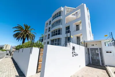 a white building with a fence and a palm tree at 4 Serene Palms in Cape Town