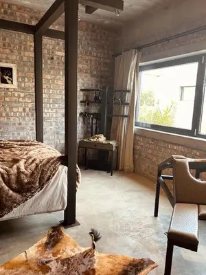 a bedroom with a bed and a window and a chair at Tether and Tease, The Citadel in Cape Town