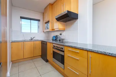 a kitchen with wooden cabinets and a stove top oven at Wake Up to the Waves - Portico in Cape Town