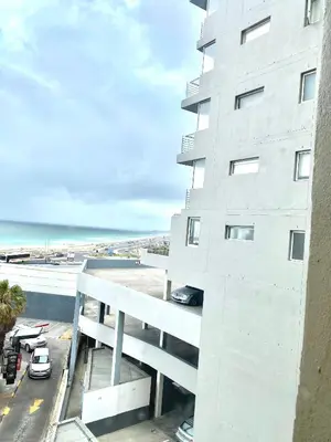 a white building with a view of the ocean at Wake Up to the Waves - Portico in Cape Town