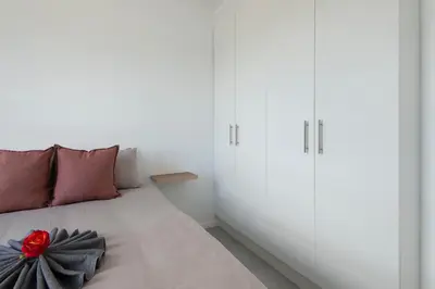 a bedroom with a bed with a red flower on it at Perlemoen Apartments in Hermanus