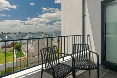 two chairs sitting on a balcony with a view at Perlemoen Apartments in Hermanus
