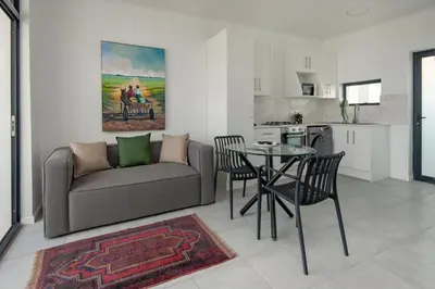 a living room with a couch and a table and chairs at Perlemoen Apartments in Hermanus