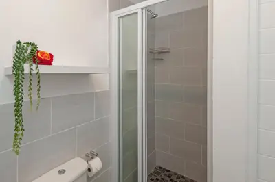 a shower with a glass door in a bathroom at Perlemoen Apartments in Hermanus