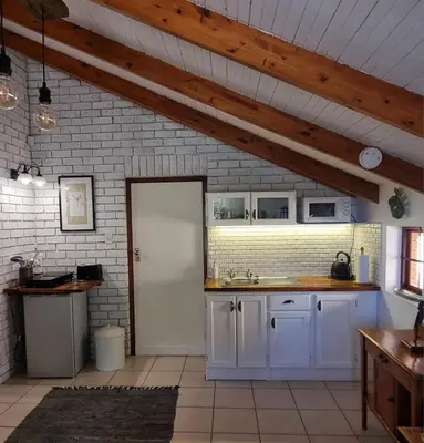 a kitchen with white cabinets and a white door at The Sculpture Yard in Gordonʼs Bay