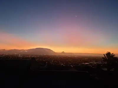 a sunset over a city with a mountain in the background at Grace Space in Plattekloof in Cape Town