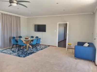 a dining room with a table and blue chairs at Grace Space in Plattekloof in Cape Town
