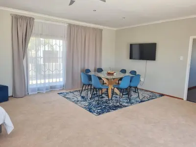 a dining room with a table and blue chairs at Grace Space in Plattekloof in Cape Town